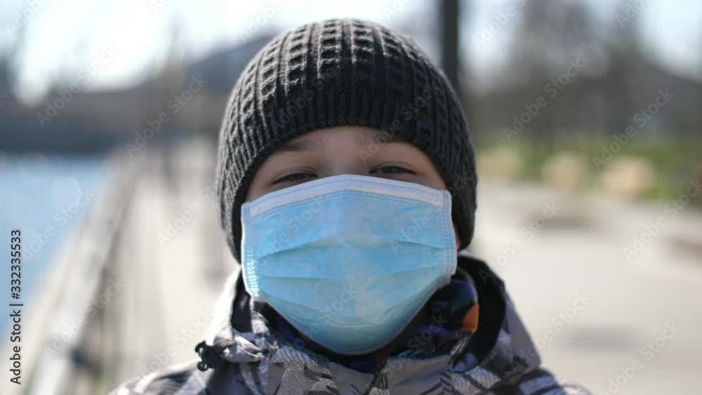 Brave boy in a protective mask and hood standing on a riverbank in spring Brave boy in a protective mask and hood standing on a riverbank in spring