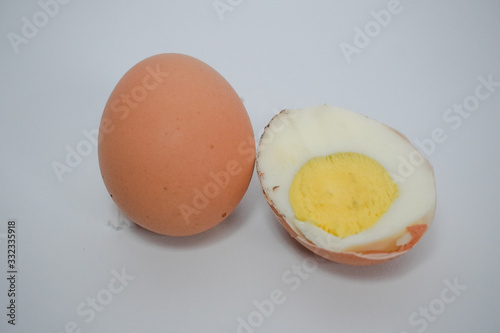 one egg and boiled egg pieces on a white background