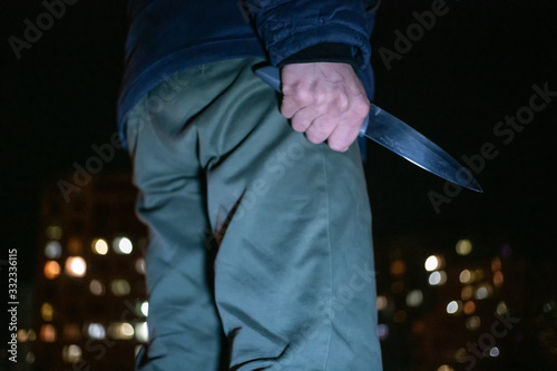 man with a knife in his hands at night on the street close-up. Concept of crimes, robbery