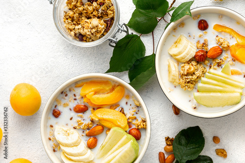 Granola bowl with fruits  nuts  milk and peanut butter in bowl on a white background. Healthy breakfast cereal top view