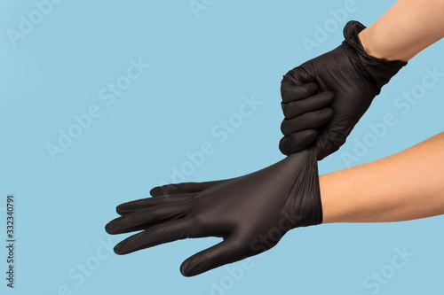 man puts on sterile black gloves on a blue background. Hazard, hygiene, control photo