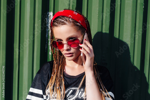 young hipster woman with bandana and braids talking on the phonesmart on sunny summer day outdoor photo