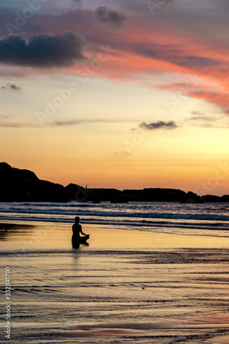 young unrecognizable woman meditating at agonda beach at sunset in goa  india