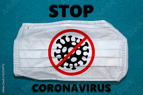 medical face mask on blue background with STOP COVID-19 symbol, Novel corona virus disease 2019, Abstract virus strain model Novel coronavirus 2019-nCoV is crossed out with red STOP sign photo