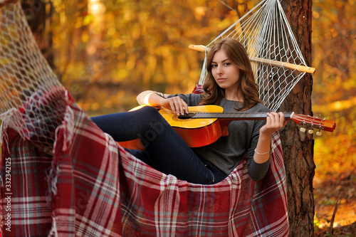 A girl in the woods on a hammock with a guitar