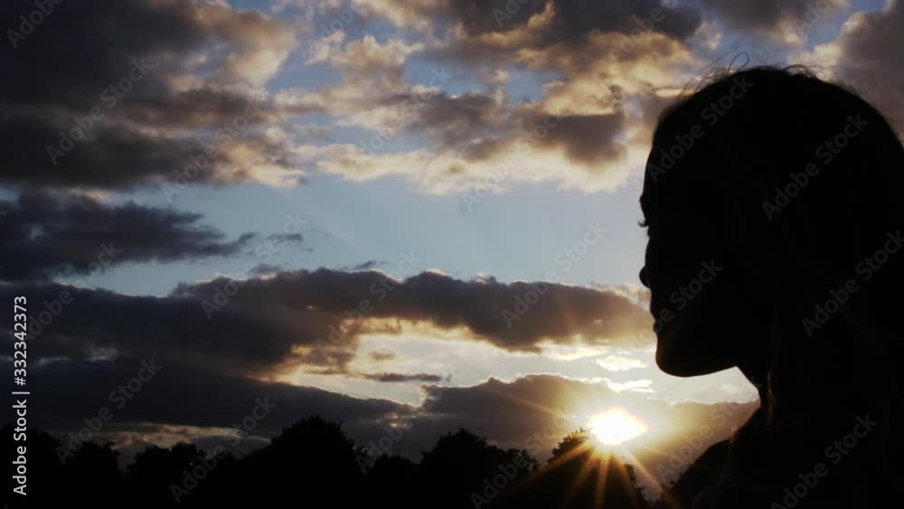 The silhouette of a long haired girl moving in and out of frame at sunset The silhouette of a long haired girl moving in and out of frame at sunset