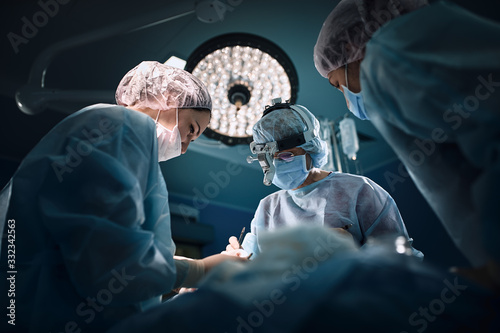 Fényképezés Medical team in the operating room, dark background