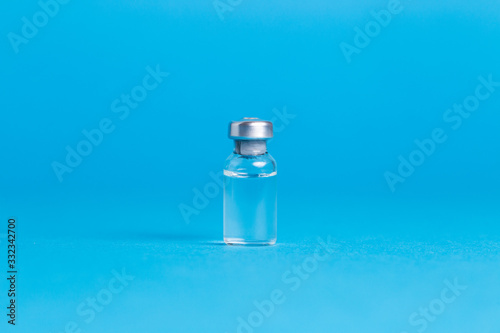 Closeup vaccine bottle on blue isolated background. No inscription, blank for advertising.