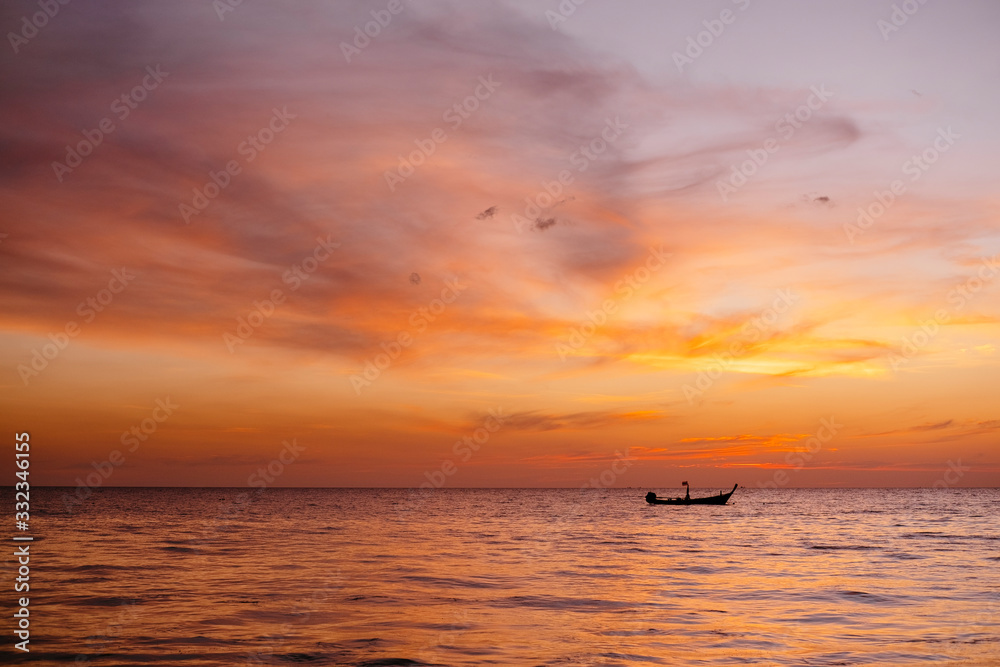 Boat at a beautiful sunset in Phuket, Thailand. Amazing seascape, Indian ocean with boat silhouette on a horizon