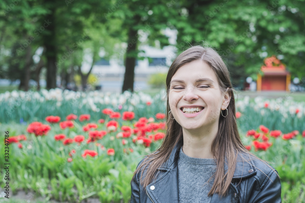 very beautiful girl portrait in a summer park on a background of red tulips very beautiful girl portrait in a summer park on a background of red tulips