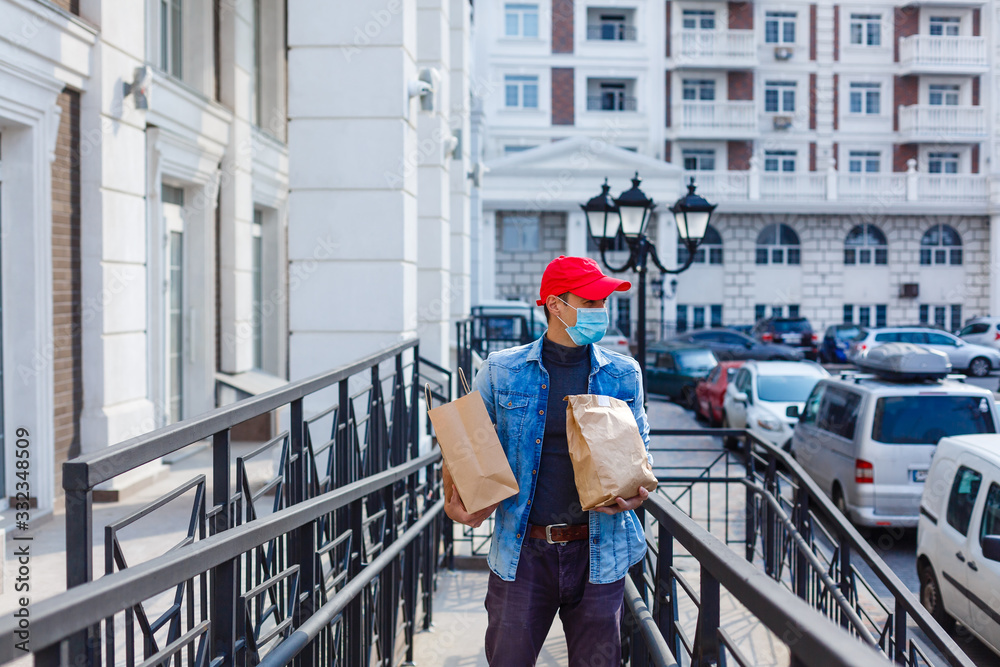 food delivery man with bags in a protective mask on his face