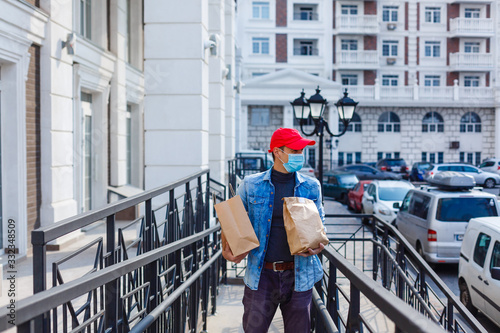 food delivery man with bags in a protective mask on his face © Angelov