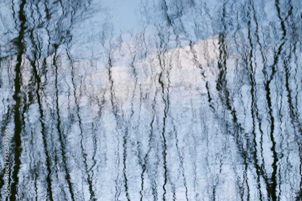 High contrast water reflection of forest. Dark trunks and light ripples. Abstract blurred shot. High contrast water reflection of forest. Dark trunks and light ripples. Abstract blurred shot.
