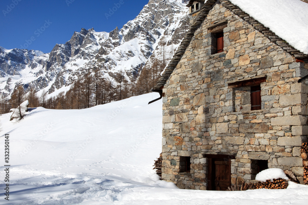 Devero Park ( Verbano-Cusio-Ossola ), Italy - January 15, 2017: A stone house at Alpe Devero Park, Ossola Valley, VCO, Piedmont, Italy Devero Park ( Verbano-Cusio-Ossola ), Italy - January 15, 2017: A stone house at Alpe Devero Park, Ossola Valley, VCO, Piedmont, Italy
