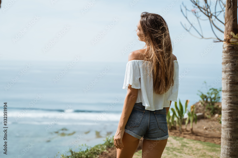 Outdoor summer portrait of young pretty woman looking to the ocean at tropical beach Outdoor summer portrait of young pretty woman looking to the ocean at tropical beach
