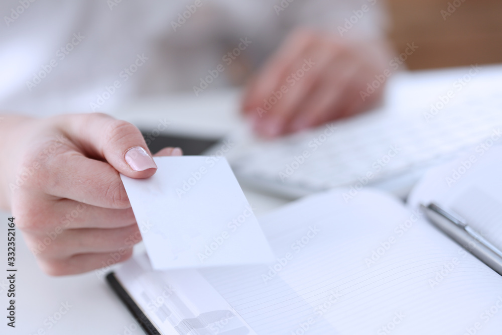 Female hand in suit give blank calling card to visitor closeup. White collar partners company name exchange, executive or ceo introducing at conference, product consultant, sale clerk concept Female hand in suit give blank calling card to visitor closeup. White collar partners company name exchange, executive or ceo introducing at conference, product consultant, sale clerk concept