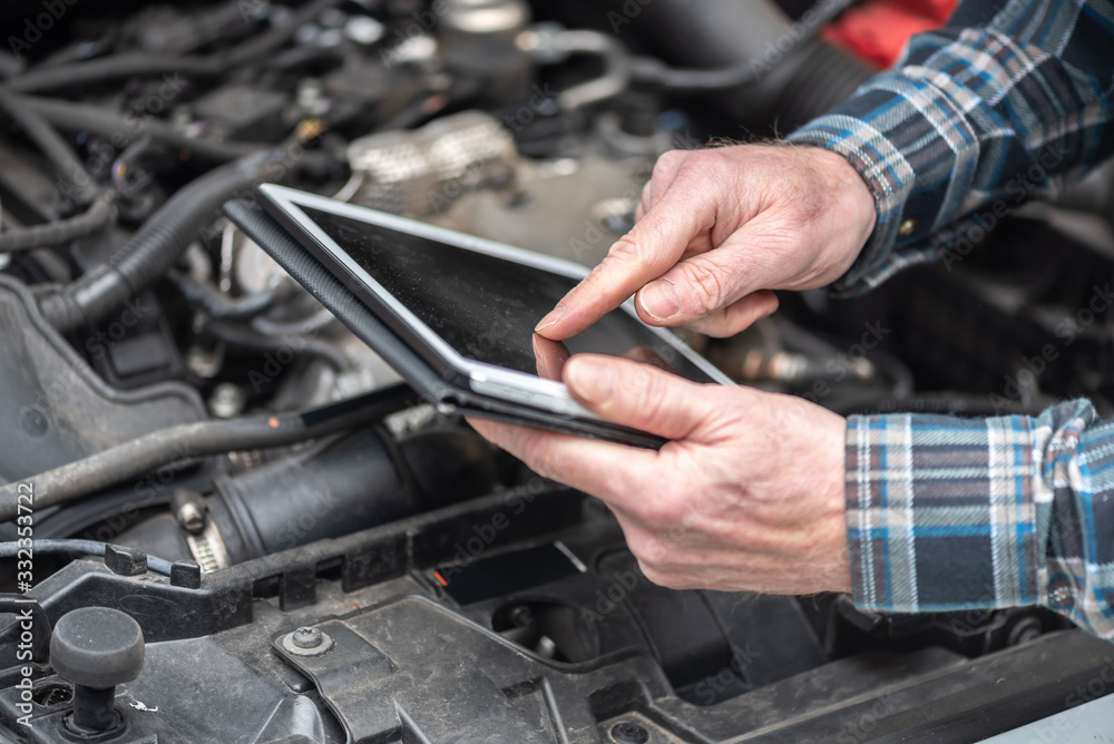 Obraz premium Mechanic using digital tablet for checking car engine