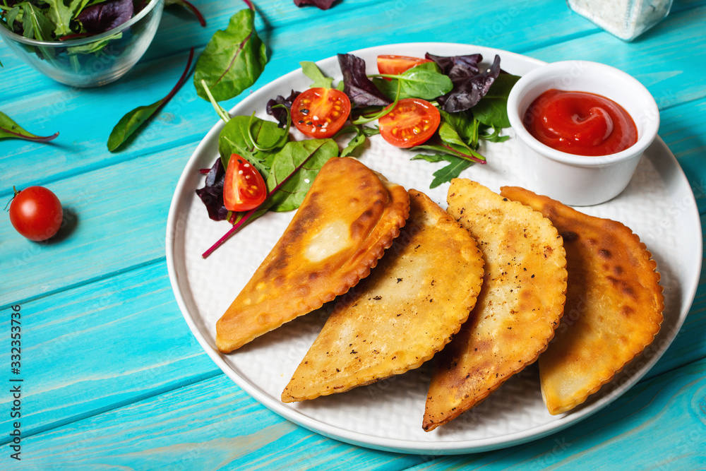 Latin American, mexican, chilean food. Traditional baked pastry empanadas with beef meat on a blue wooden background Latin American, mexican, chilean food. Traditional baked pastry empanadas with beef meat on a blue wooden background
