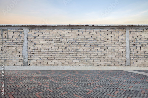 Gray brick wall with empty brick pavement