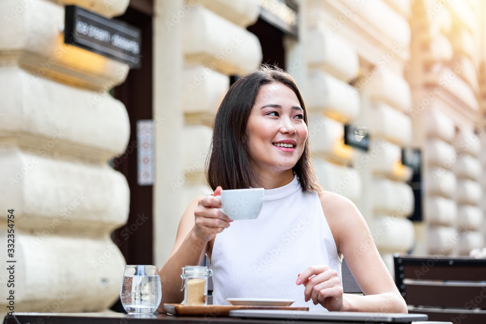 Beautiful Asian young woman with cup of coffee. Woman enjoys fresh coffee in the morning with sunrise at coffe shop Beautiful woman drinking coffee in the morning sitting outdoors Beautiful Asian young woman with cup of coffee. Woman enjoys fresh coffee in the morning with sunrise at coffe shop Beautiful woman drinking coffee in the morning sitting outdoors