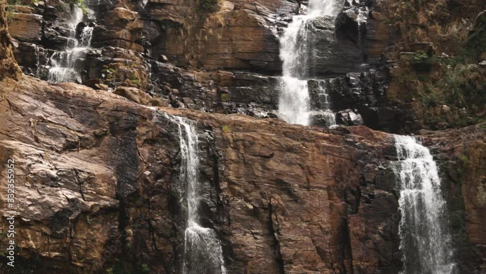 Waterfall in a mountainous tropical area. Water flows down a brown rock. Natural nature. Waterfall in a mountainous tropical area. Water flows down a brown rock. Natural nature.