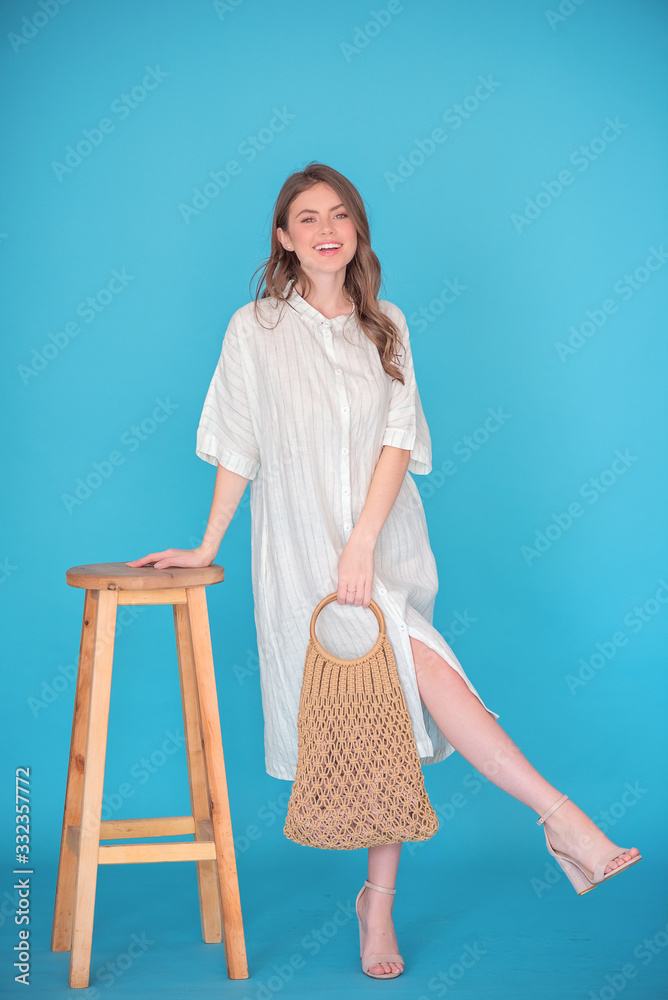 Attractive young girl with long brunette hair with eco friendly bag staying next to the wooden chair. Zero wasty. Stop polution be resonsible Attractive young girl with long brunette hair with eco friendly bag staying next to the wooden chair. Zero wasty. Stop polution be resonsible