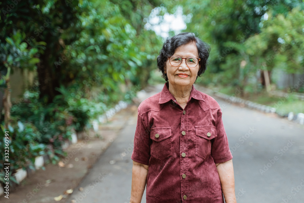 close up confident Asian grandma wearing eyes glasses stand in the park close up confident Asian grandma wearing eyes glasses stand in the park
