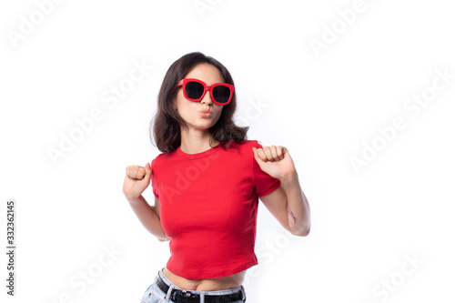 Attractive beautiful young woman smiling cheerfully with long hair brunette wearing red casual t shirt fashion lifestyle portrait pretty woman in sunglasses posing isolated on white background.