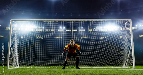 Goalkeeper is trying to save from a goal on an empty soccer stadium. No spectators on the tribunes. Stadium is made in 3d.