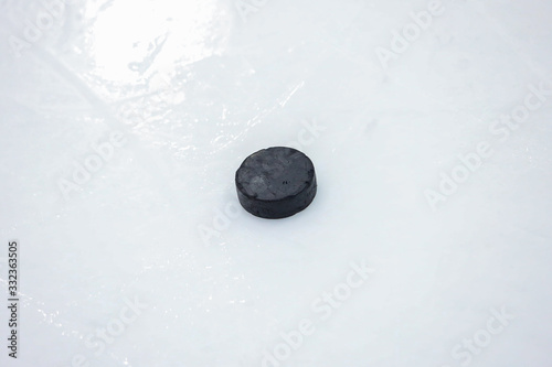 Old black Ice Hockey puck on ice arena hockey rink.