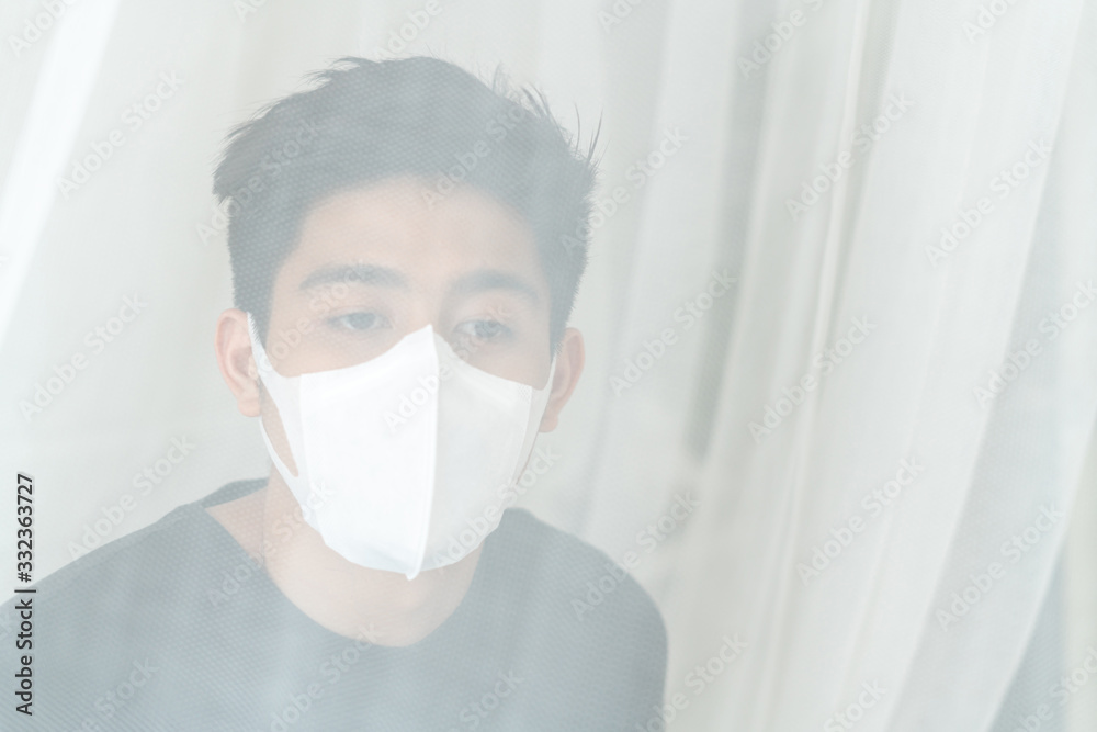Asian man wearing Face Mask to protect feeling sick headache and cough because of Coronavirus covid-19 in quarantine room , Quarantine yourself to protect spread Covid-19 Coronavirus Asian man wearing Face Mask to protect feeling sick headache and cough because of Coronavirus covid-19 in quarantine room , Quarantine yourself to protect spread Covid-19 Coronavirus