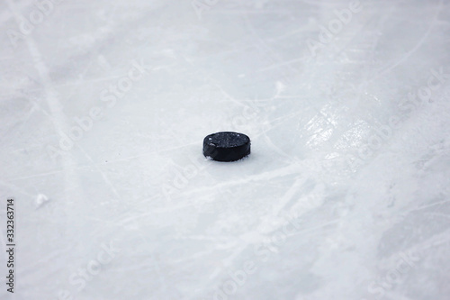 Black, old ice hockey puck on ice rink ice.
