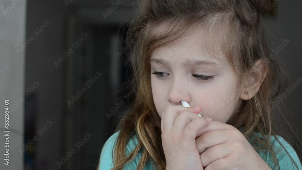 Little charming girl child sprays a runny nose spray in her nose Little charming girl child sprays a runny nose spray in her nose