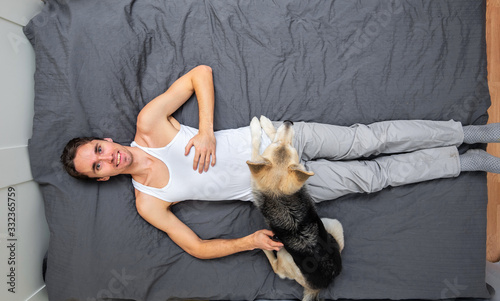 Man and dogs lying on bed with gray sheet