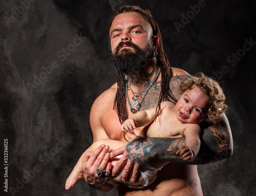 sporty brutal man holds in arms a little baby