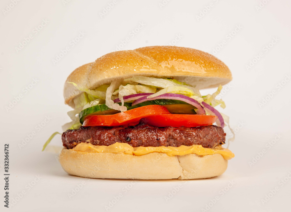 Burger with tomato and veggies over a white background Burger with tomato and veggies over a white background