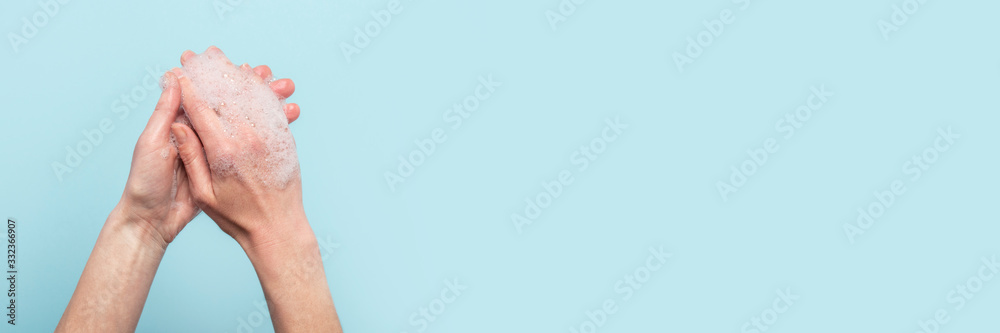 Fototapeta premium Hand washing. Soapy female hands on a blue background. Concept of the rules of washing and handling hands. Top view, flat lay. Banner