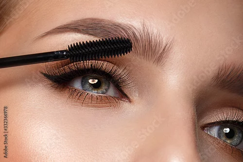 Obraz Beautiful girl with sexy lips and classic makeup with cosmetic mascara brush in hand. Beauty face.