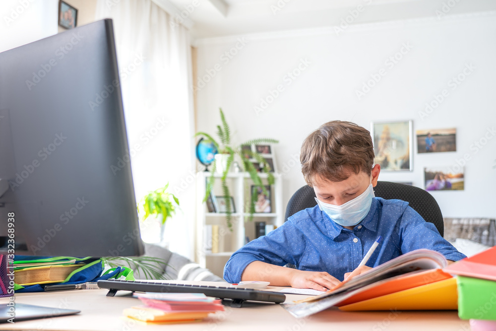 boy in face mask using computer, doing homework during coronavirus quarantine boy in face mask using computer, doing homework during coronavirus quarantine