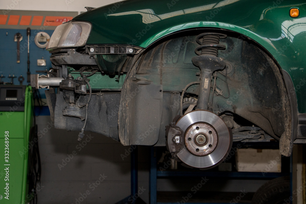 green car in mechanical workshop, detail of brake and shock absorber without wheel green car in mechanical workshop, detail of brake and shock absorber without wheel
