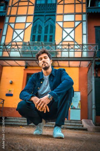 Foto A young enterprising businessman crouched on the ground with an orange house in