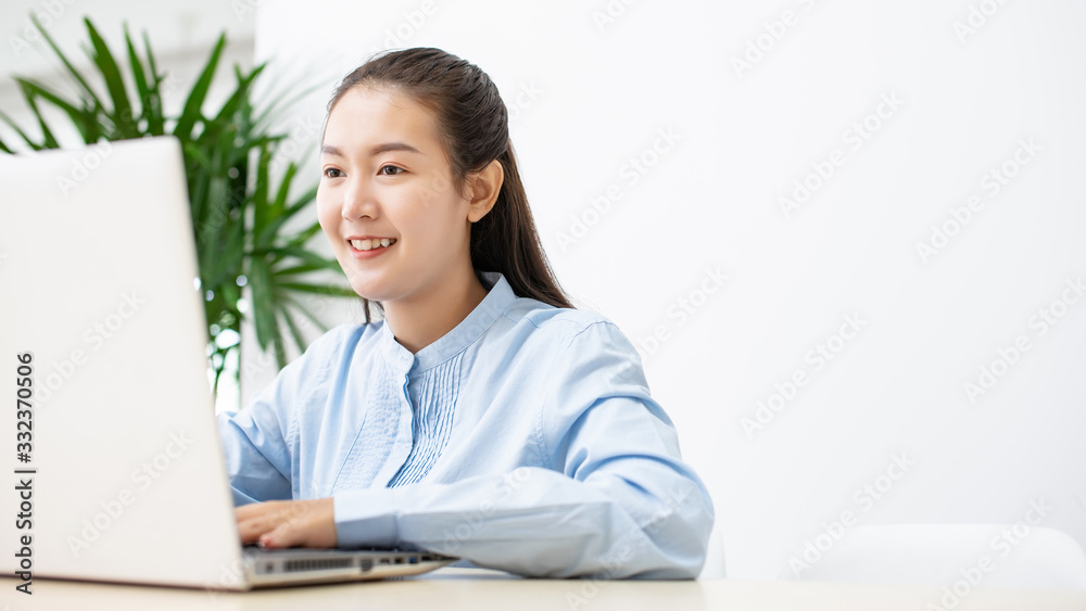 Asian success businesswoman happy using laptop computer connect internet working from home in white room with copy space Asian success businesswoman happy using laptop computer connect internet working from home in white room with copy space