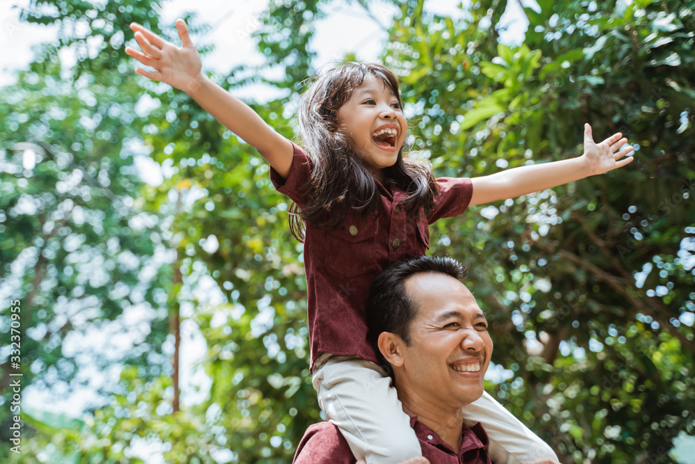 asian father carrying on neck smiling daughter while walking in the park asian father carrying on neck smiling daughter while walking in the park