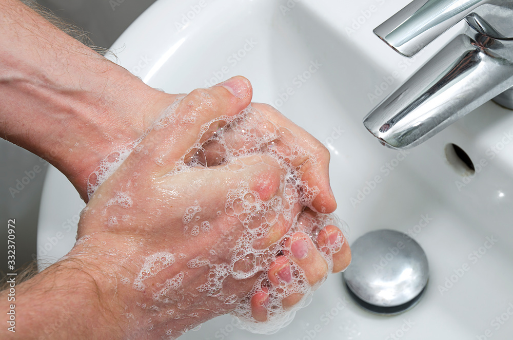 Fototapeta premium Man washing hands in the bathroom. Hands close up with hand-wash foam. Washing hands rubbing with soap man for corona virus prevention. 