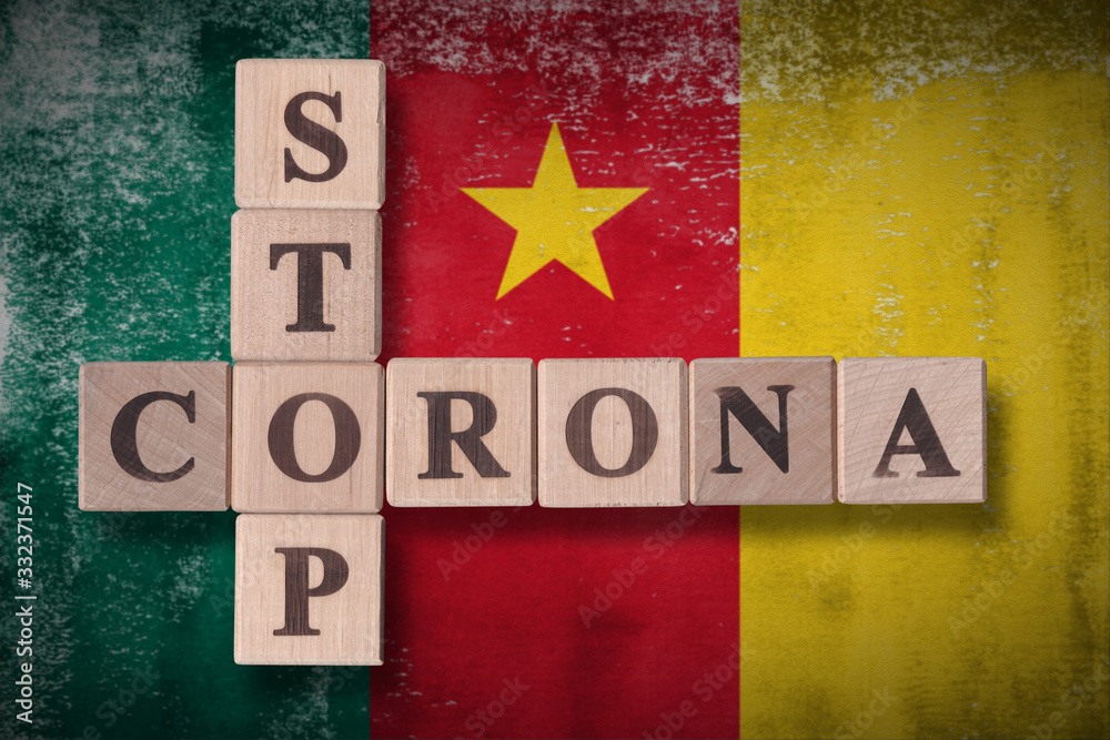 Obraz premium Flag of Cameroon with wooden cubes spelling STOP CORONA on it. 2019 - 2020 Novel Coronavirus (2019-nCoV) concept art, for an outbreak occurs in Cameroon.