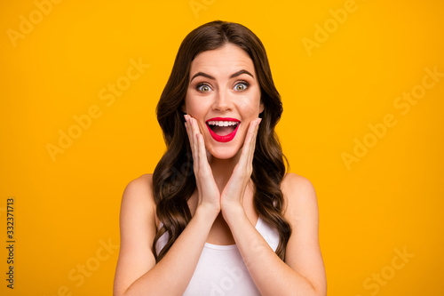 Closeup photo of beautiful pretty lady open mouth arms on cheeks positive good mood long brunette hairdo surprised wear white tank-top isolated bright yellow color background