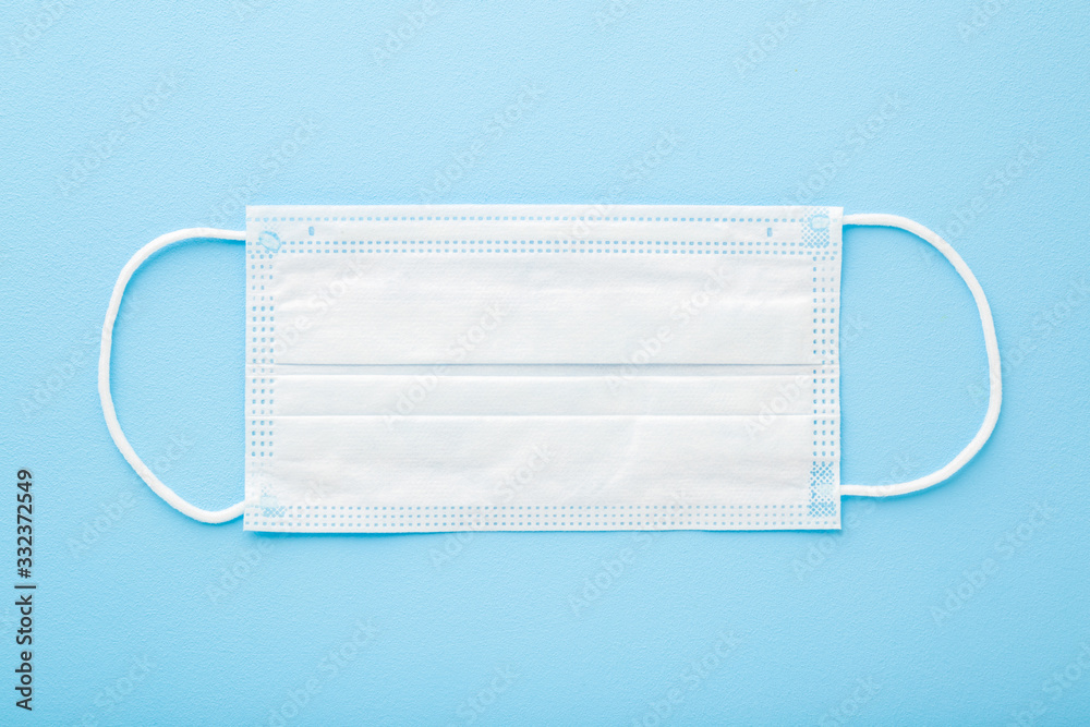 White respirator mask for mouth and nose covering. Light pastel blue table background. First protection in dangerous virus time. Healthcare concept. Closeup. Top down view. White respirator mask for mouth and nose covering. Light pastel blue table background. First protection in dangerous virus time. Healthcare concept. Closeup. Top down view.
