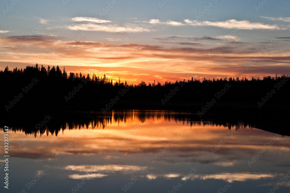 sunset clouds are reflected in the calm mirror water of the lake