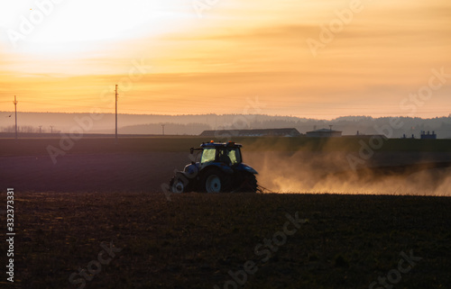 Tractor silhouette in the field on the orange-yellow sunset