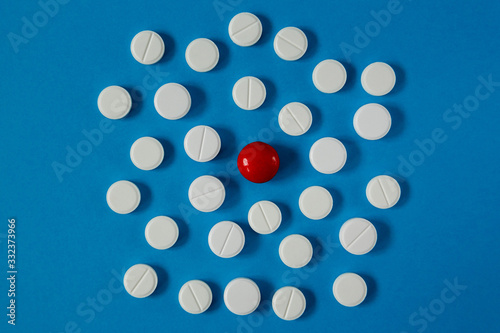 many white pills and one red on a blue background